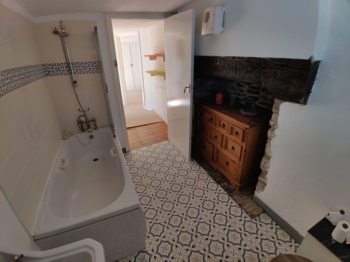 The bathroom with a shower over the bath