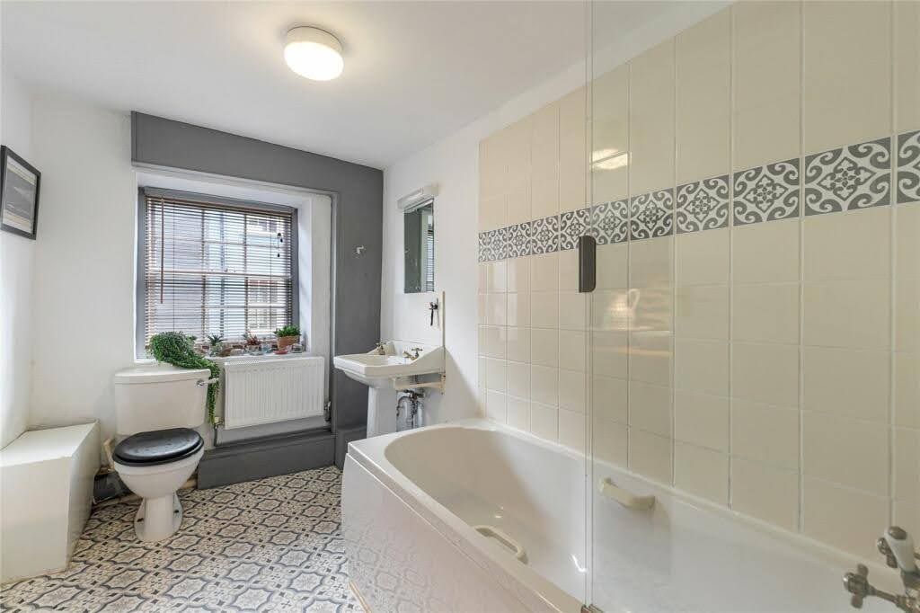 Bright bathroom with a bath and a patterned tiled floor