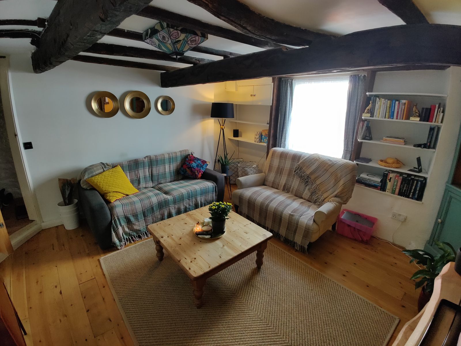Characterful living room with exposed beams, wood floors and a sunny yellow wall